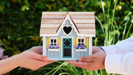 An agent and a client holding a model of a house