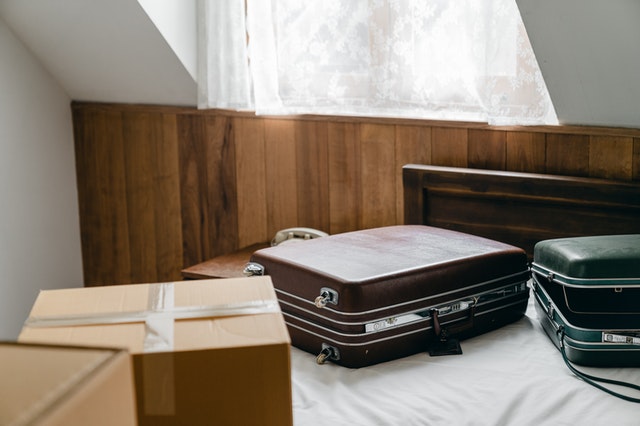 Luggage and boxes on a bed. 