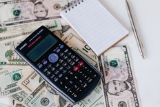 A calculator and a notepad on dollar bills.