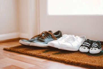 Three pairs of shoes on a doormat.