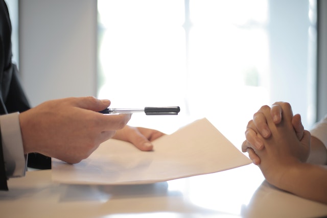 A person holding a paper and a pen