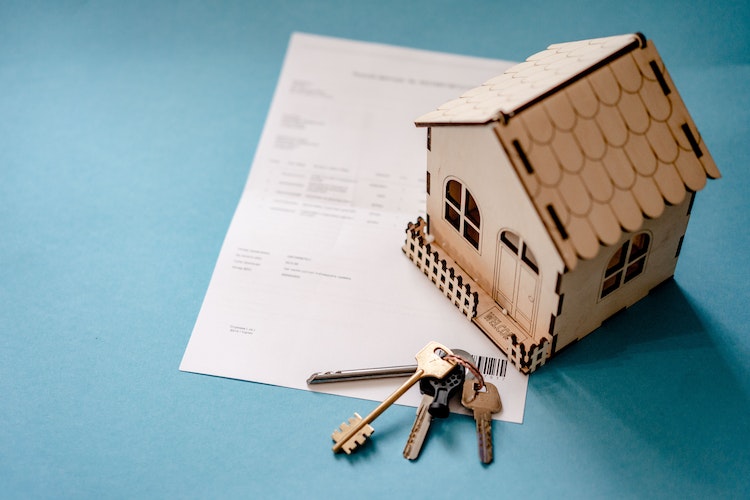 A small wooden house, keys, and a paper