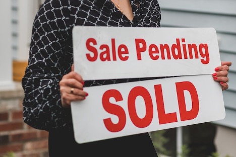 A person holding a “sold” sign