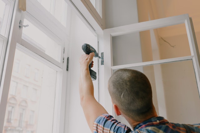 Man repairing a window with a drill