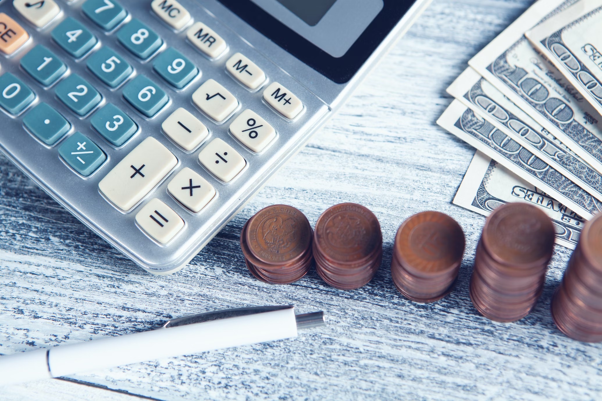 A calculator next to paper notes and bronze coins.
