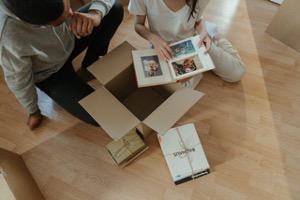 Two people arranging picture frames on the floor in a new home